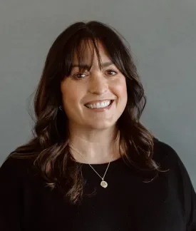 Brenna Love wearing a black shirt in front of a gray background.