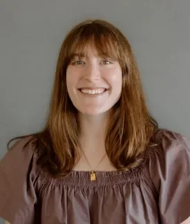 Claire Ristow wearing a brown boho shirt in front of a gray background.
