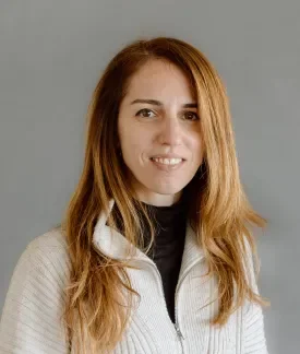 Cristina Chumillas in a white quarter zip pullover in front of a gray background.