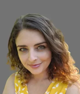 Helena McCabe wearing a yellow sleeveless top with white polk dots in front of a gray background.