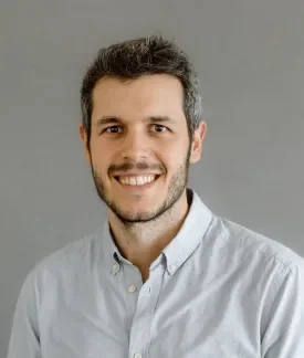 Ignacio Sanchez Holgueras wearing a white button down shirt in front of a gray background.