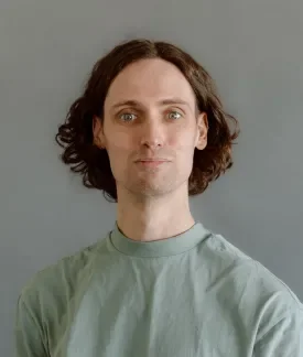 James Bain wearing a light green t-shirt in front of a gray background.