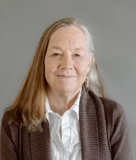 Karen Stevenson wearing a white button down shirt and blazer with gray backdrop behind her.