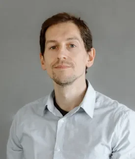 Salva Molina Moreno wearing a light gray button down shirt in front of a gray background.