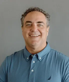 Sean Lange wearing a teal polo shirt in front of a gray background.