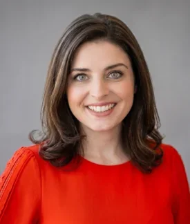 Headshot of Helena McCabe in a red dress. Mid-30's, brown hair, green eyes, caucasian