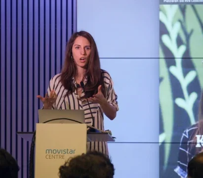 Cristina stands on a stage in front of a podium that reads, movistar centre.