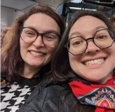 Sally and Marissa smile while they take a selfie.