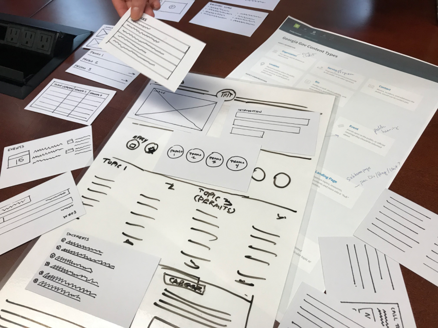Paper wireframe components and laminated backgrounds spread out on a table