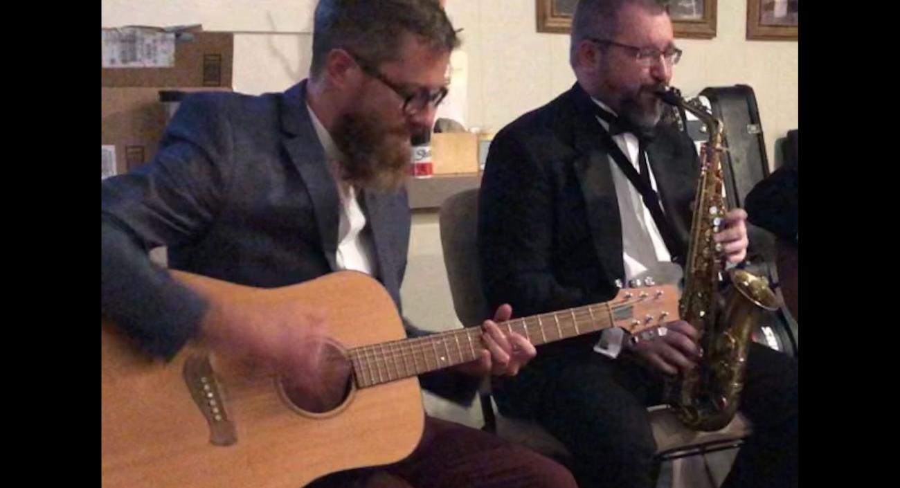 Lullabot team members playing a guitar and a saxophone.