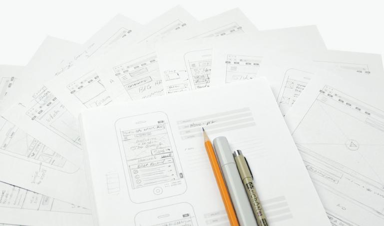 Pens sitting on mobile design sketches