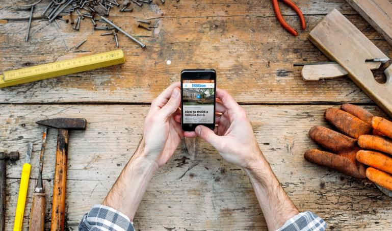 Hands holding smartphone over a workbench