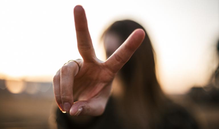Woman making peace sign in front of her face.