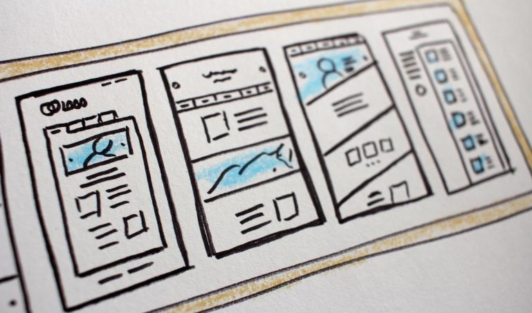four different website mockups drawn on a whiteboard
