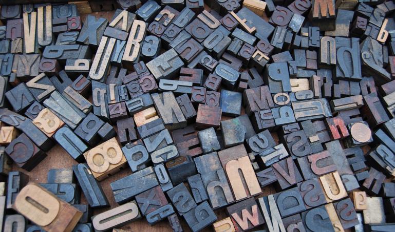 A jumble of wood letters in various shapes, sizes, and colors.