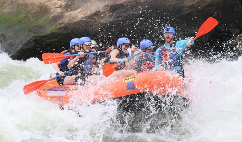 Several people on a raft navigating whitewater rapids and having a great time