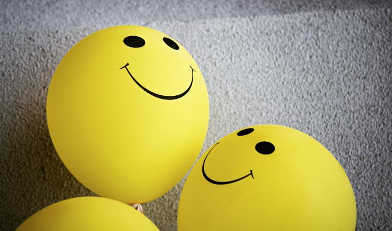 Three yellow balloons with black smiley faces