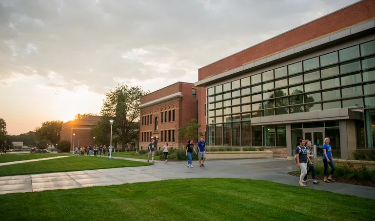 SDSU campus with students walking by building that has a wall of windows