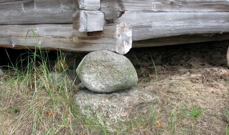 A simple foundation showing a log cabin resting on a stone