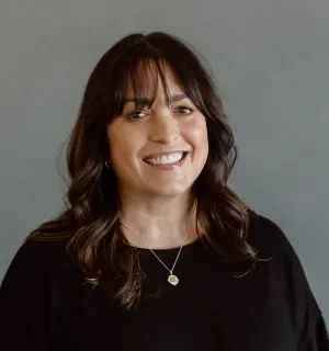 Brenna Love wearing a black shirt in front of a gray background.