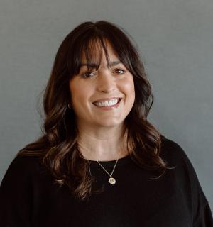 Brenna Love wearing a black shirt in front of a gray background.