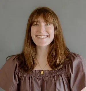 Claire Ristow wearing a brown boho shirt in front of a gray background.