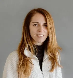 Cristina Chumillas in a white quarter zip pullover in front of a gray background.