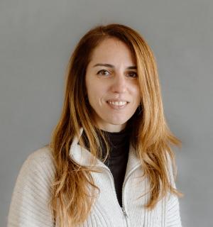 Cristina Chumillas in a white quarter zip pullover in front of a gray background.