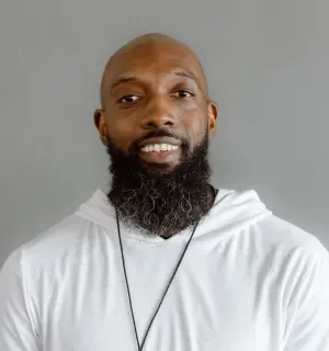 Flash Gooden wearing a white hoodie in front of a gray background.