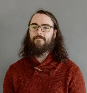 Hunter MacDermot wearing a read pullover in front of a gray background.