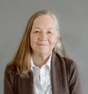 Karen Stevenson wearing a white button down shirt and blazer with gray backdrop behind her.