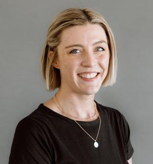 Laura Donelan wearing a black t-shirt in front of a gray background.