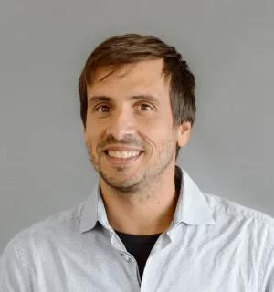 Mateu Aguilo Bosch wearing a white button down shirt with black t-shirt underneath in front of a gray background.