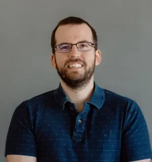 Owen Bush wearing a dark blue polo shirt in front of a gray background.