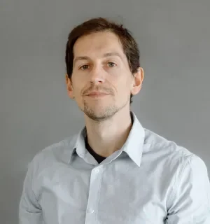 Salva Molina Moreno wearing a light gray button down shirt in front of a gray background.