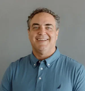 Sean Lange wearing a teal polo shirt in front of a gray background.