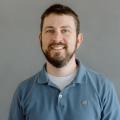 Adam Varn wearing a teal polo shirt in front of a gray background.