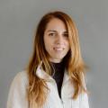 Cristina Chumillas in a white quarter zip pullover in front of a gray background.